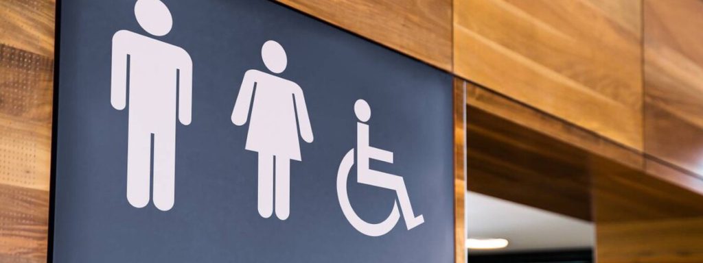 Accessible toilet sign with icons for male, female, and wheelchair users.