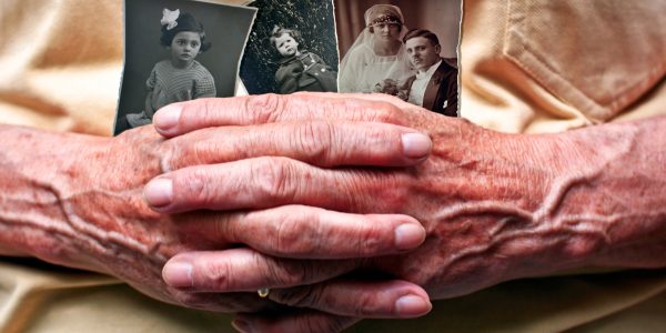 Elderly hands gently holding black and white family photographs.