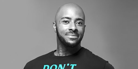 Confident man with tattoos wearing a T-shirt with the word "DON'T" printed on it.