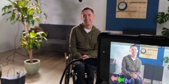 Tyler sat in his wheelchair looking at the camera while being interviewed for Tyler's story.